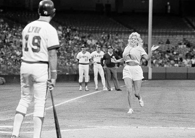 “Morganna “The Kissing Bandit” running onto the field toward California Angels outfielder Fred Lynn during a game at Anaheim Stadium, Anaheim, California, June 9, 1983.”